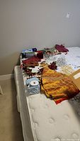 Christmas gift bags, tree skirt, ribbons, and assorted decor items placed on a mattress
