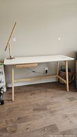 Full view of the desk showing the white melamine tabletop with wooden legs and an adjustable wooden lamp on top (lamp not included in sale).