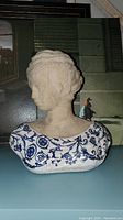 Front view of white bust with blue floral design, female figure from shoulders up.