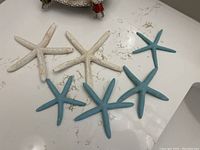 Six starfish decorations, three white and three blue, displayed on a flat surface