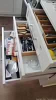 Three drawers with flatware, kitchen utensils, towels, napkins, and kitchen accessories.