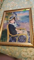 Full view of the reproduction oil painting showing the woman seated in a wicker chair by the sea.