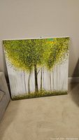 Front view of the square canvas painting displaying three stylized trees with green and yellow leaves on white and gray background.