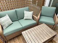 Full set showing wicker loveseat, armchair, coffee table, cushions and pillows