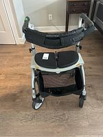 Front view of the Evolution rollator walker showing black padded split seat, basket underneath, and padded backrest.