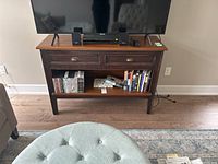 Front view of wooden table with TV and books displayed on shelf