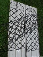 Set of three metal garden trellises arranged on a white panel with grass background, showing full items and some wear.