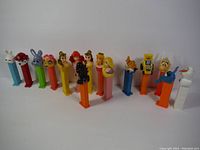 Photo of 15 vintage Pez dispensers with various colorful character heads including Disney princesses, animals, and other figures.