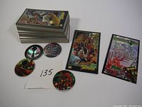 Stack of approximately 75-80 Spawn trading cards with five circular tokens next to them alongside a note marked "135".