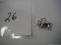 Sterling silver pig charm shown from side angle to highlight details and attachment loop.