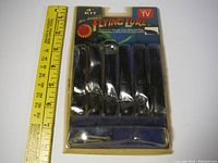 Vintage sealed kit of The Amazing Flying Lure 4 inch with 6 baits and 2 jig heads, showing packaging and ruler for scale.