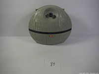 Exterior view of the closed Death Star play set showing spherical shape, grey detailed surface, and orange latch.