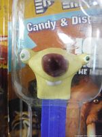 Close-up of PEZ candy dispenser with sloth character head on blue stem in unopened packaging