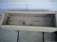 Top view of the wicker plant stand showing interior of the planter box with worn and chipped paint.