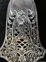 Close-up of the pastry server blade showing detailed floral and lattice cutout patterns in 800 silver.