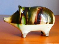 Front and side view of the ceramic piggy bank showing drip glaze and chip on snout.