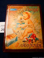 Front/top view of antique Hannoversche Bahlsen biscuit tin showing colorful lithographed baby and biscuit design.