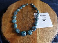 Full view of chunky graduated turquoise bead necklace laid flat on wooden surface with MaxSold card.