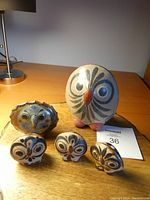 Front view of five hand-painted Mexican pottery owls on a wooden surface, showing various sizes and designs.