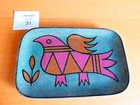 Top view of rectangular ceramic platter displaying colorful stylized bird in pink, brown and orange on blue background