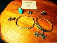 Full lot of Mexican and Southwestern style jewelry including bracelets, earrings, and rings on wooden surface.