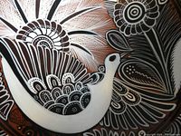 Close-up showing detailed hand-painted design of a bird and flowers in black, white, and brown hues on bowl interior.