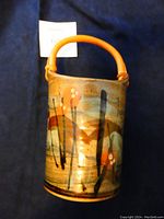 Front view showing the hand-painted floral design and bamboo handle on the pottery container.