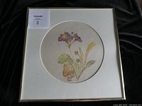 Full view of framed primula painting on round rice paper with gold-tone frame and white mat.