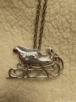 Close-up front view of detailed sterling silver sleigh pendant showing polished finish and intricate scrollwork on runners.