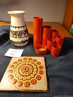 Lot view showing all items: ceramic signed vase, Villeroy & Boch tile and 7 orange metal pencil holders of different sizes