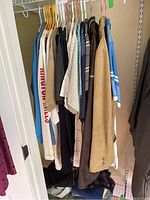 Photo of men's shirts and jackets hanging on rack in various sizes and neutral colors