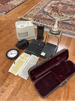 Photo of the lot on wooden floor showing violin case, keyboards, humidifiers, heater, clock, lamp base.