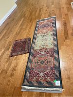 Photo of Persian runner rug and small heavily worn mat on wooden floor