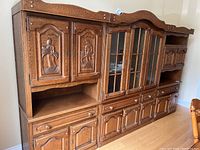 Wide view showing all three sections of the wall unit with elaborate carvings and glass doors