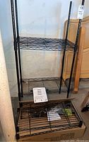 Amazon Basics 4-shelf adjustable metal storage shelf unit standing upright with two shelves attached and two shelves still packaged flat in the box underneath.