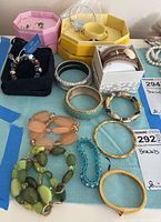 Image showing various bracelets and a pair of earrings arranged on a light blue fabric with boxes in background.