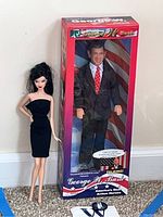 Photo showing both George W. Bush doll in box and Barbie fashion doll side by side.