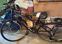 Blue Globe bicycle with step-through frame, flat front tire, black seat and upright handlebars in indoor storage setting