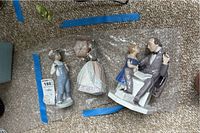 Three Lladro porcelain figurines laid on a carpet in protective wrapping
