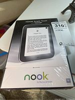 Sealed box of Nook Simple Touch e-reader with GlowLight, showing front of packaging with device image and text.