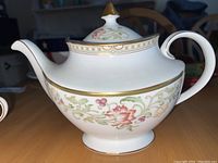 Full view of the Royal Doulton porcelain tea pot showing the floral pattern on the body, handle, and spout, with gold trim.