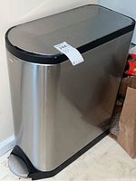 Rectangular stainless steel step trash can with black plastic lid and foot pedal.