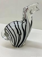 Side and front view of Italian glass zebra paperweight showing clear glass head and tail with black striped white body.