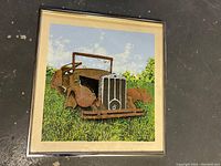 Full view of the framed print depicting an old rusty car in a field.