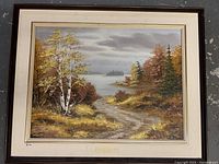 Full view of the framed oil painting showing the forest landscape with the lake and distant island.