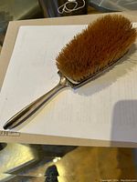 Front view of the Birks sterling silver hair brush showing the handle and natural bristles.
