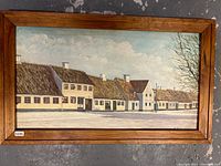 Front view of signed oil on board painting showing a row of houses in a winter scene.