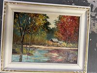 Full view of the framed oil painting showing a landscape with trees, water, and a house.