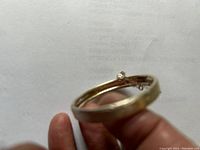 Side view of the silver baby bangle showing the hinged clasp and checkered pattern detail.