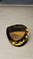 Top-down image of a large pear-shaped golden citrine gemstone indicating its color, clarity, and cut facets.